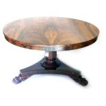 A William IV rosewood tilt top dining table, the circular top on a heavy stem, terminating in platfo