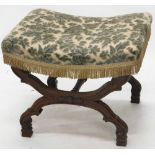 An early 20thC heavily carved Continental stool, with overstuffed seat in floral material, on X shap