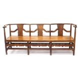 An oak Arts and Crafts style settle, with serpentine back, on turned supports with a carved frieze,