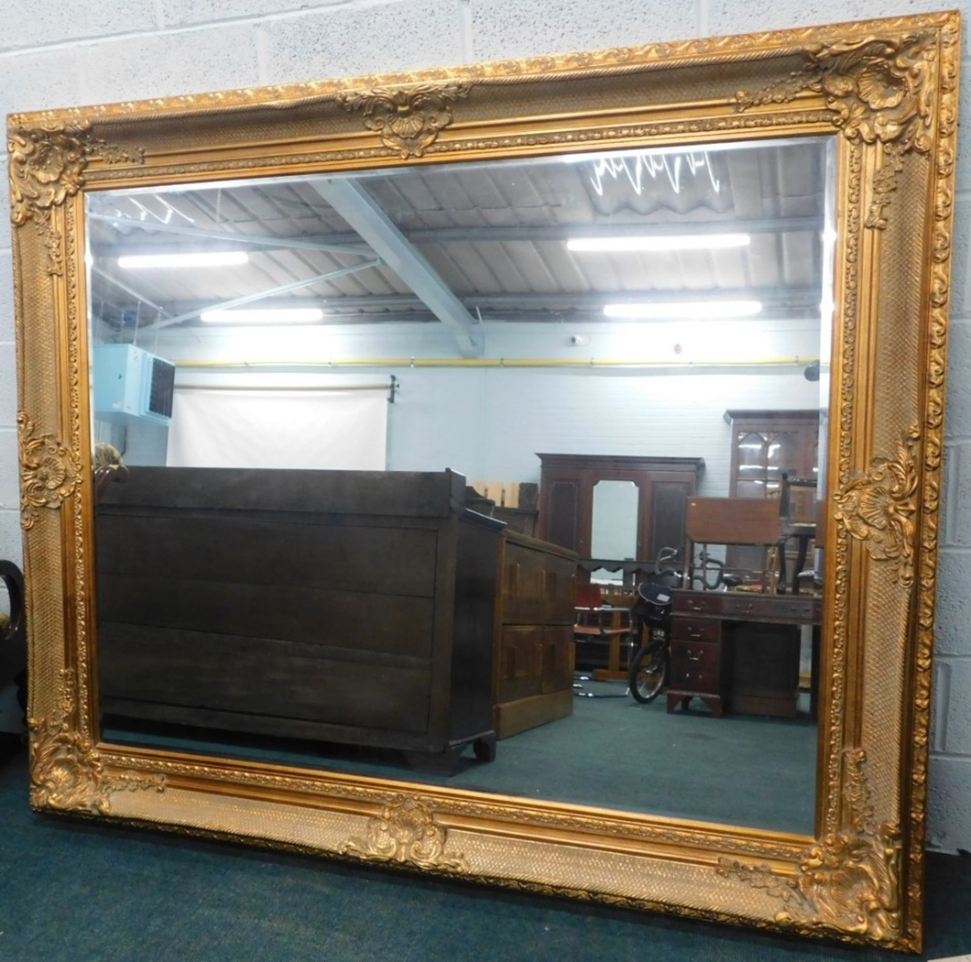 A very large giltwood rococo style hanging mirror, the bevel glass, the moulded frame decorated with