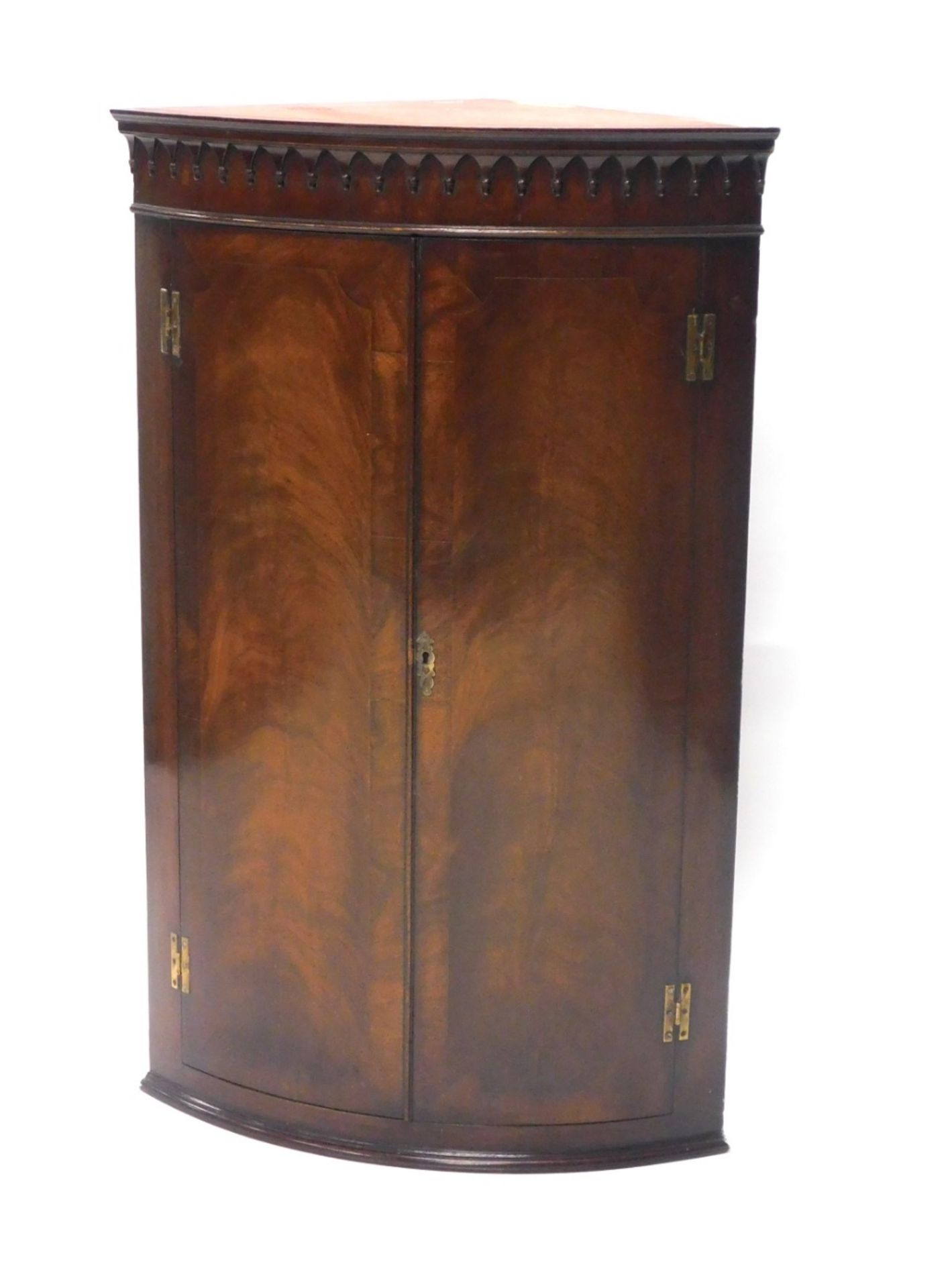 A mahogany hanging corner cabinet, with a carved top raised above two flame mahogany doors, with she