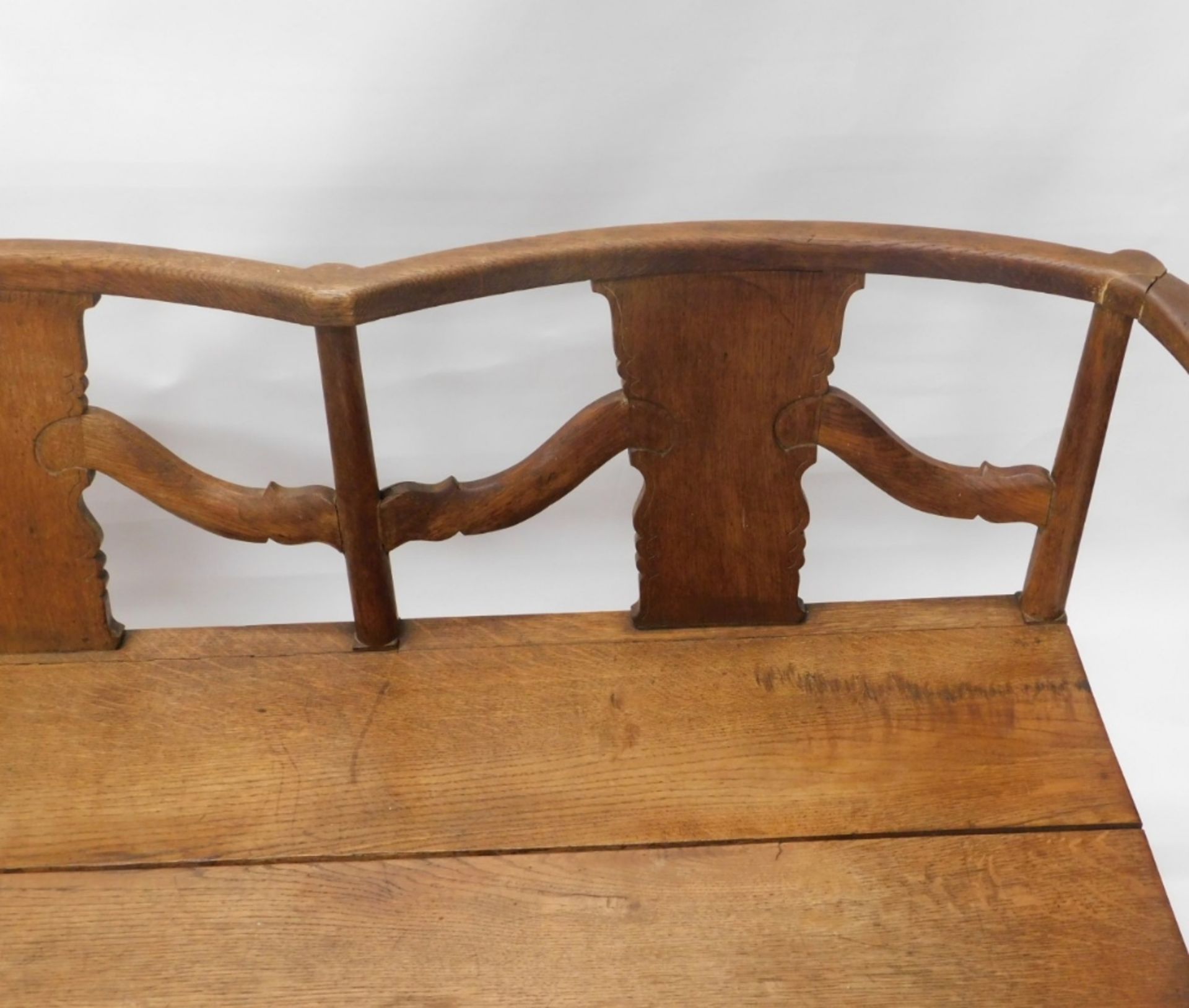 An oak Arts and Crafts style settle, with serpentine back, on turned supports with a carved frieze, - Image 2 of 2