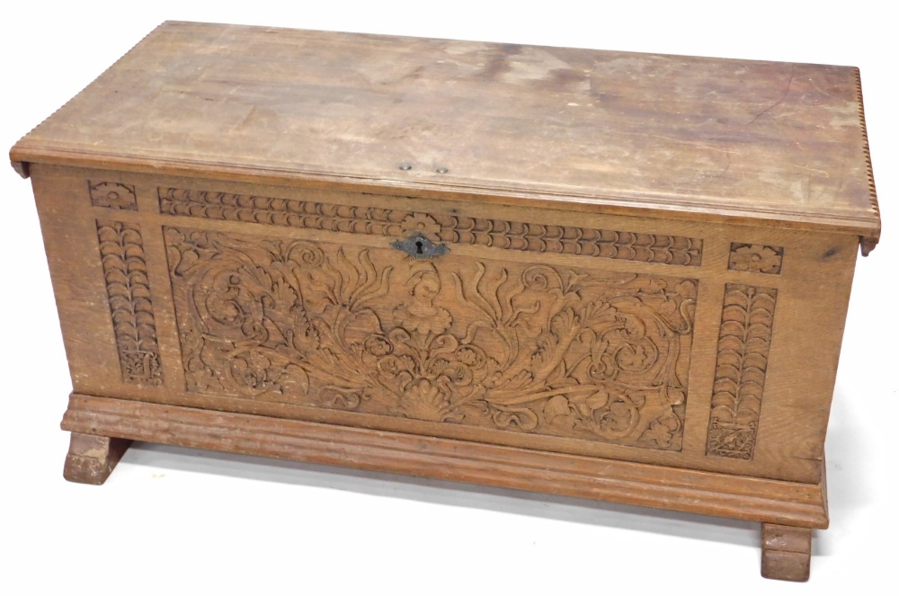 A heavily carved 19thC French oak coffer, the rectangular top revealing a plain interior, above a he