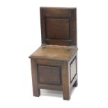 A child's oak chair, with hinged lid, panelled back and sides, on stiles, 72cm high.