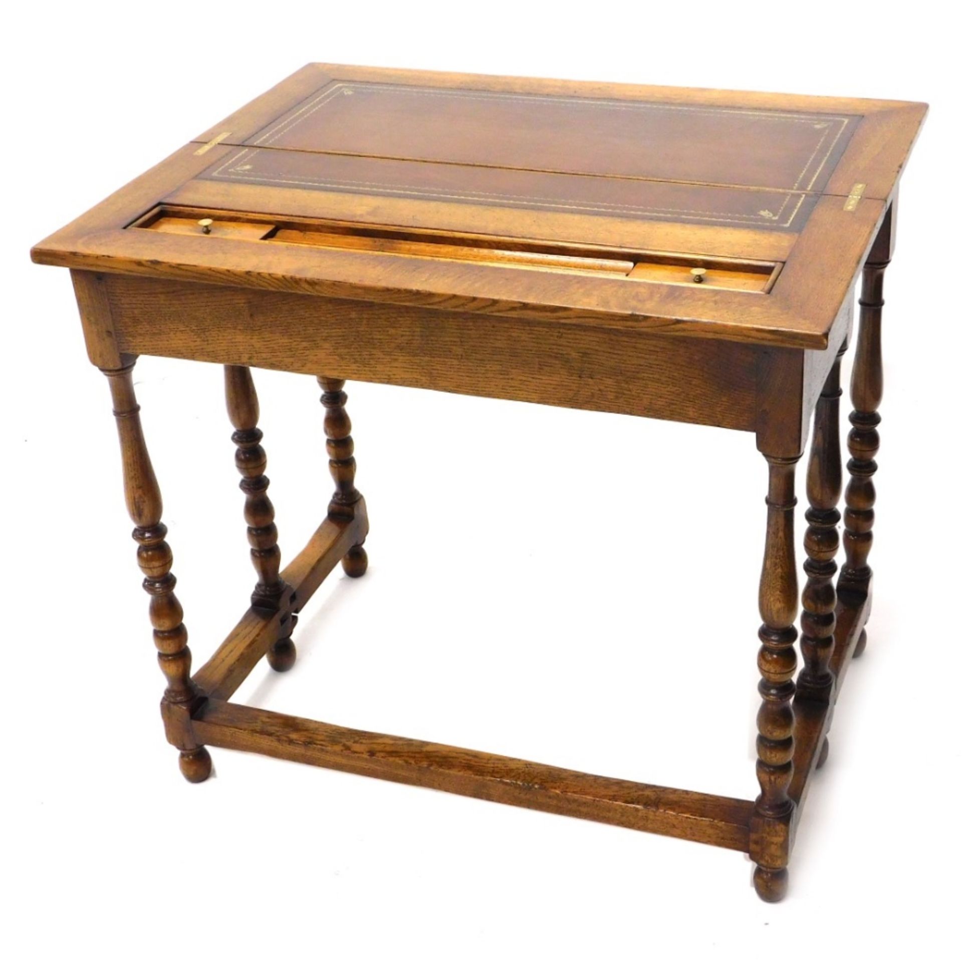 A 20thC oak fold over desk, with a brown leather tooled section with another section for ink bottles