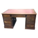 A 20thC oak twin pedestal desk, with tooled red leather top above an arrangement of drawers, on bloc