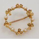 A circular seed pearl set brooch, in a berry and clover leaf alternating design, set in yellow metal