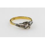 An Art Deco diamond ring, set with a brilliant cut diamond in a square mount, with shoulders each se