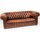 A tan leather three seater Chesterfield sofa, with button back and seat, raised on turned legs, 204c
