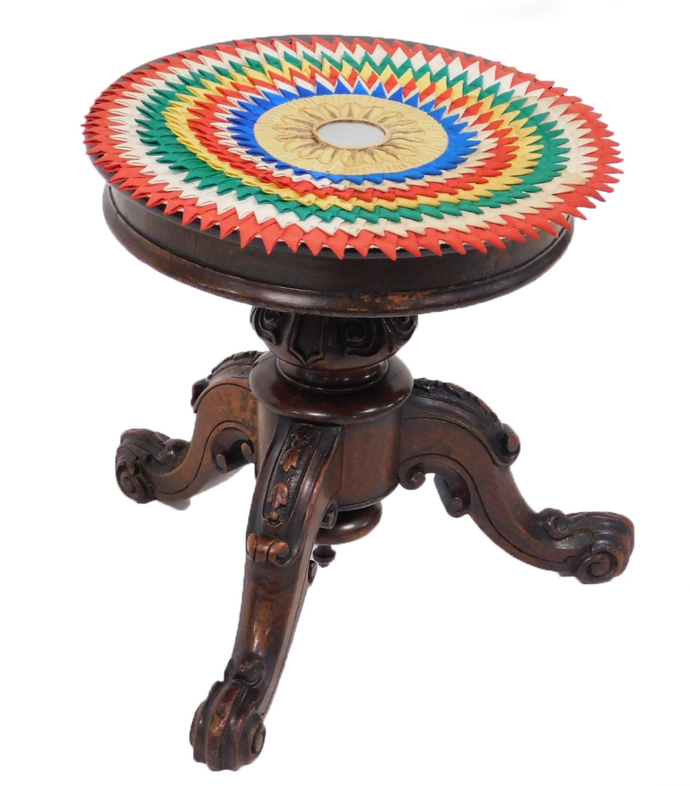 A Victorian mahogany piano stool, the circular revolving top raised on a scroll and leaf carved colu