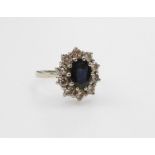 An 18ct white gold sapphire and diamond ring, the oval cut sapphire in a surround of diamonds, diamo