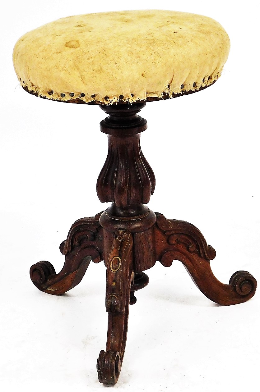 A Victorian mahogany revolving piano stool, with an overstuffed seat, raised on a turned and fluted