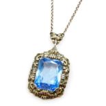 A silver and blue stone set pendant, possibly an aquamarine, rectangular facet cut, in a foliate pen