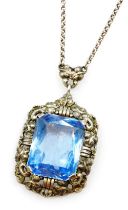 A silver and blue stone set pendant, possibly an aquamarine, rectangular facet cut, in a foliate pen