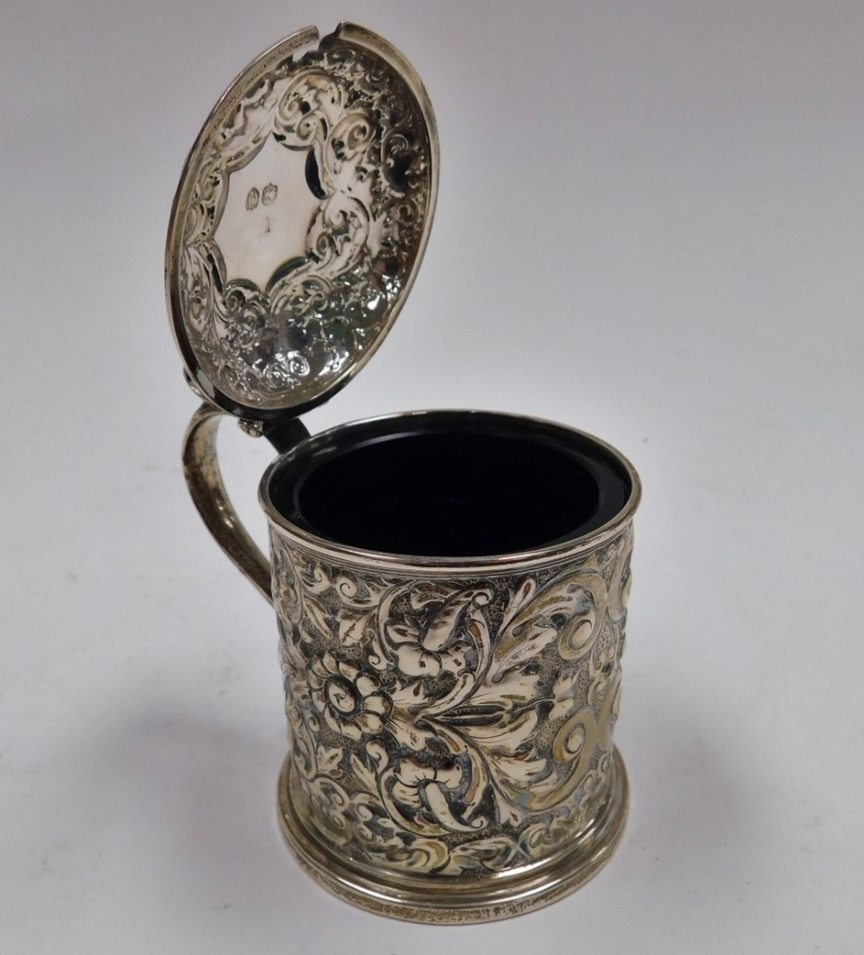 A Victorian silver mustard pot, the body and lid embossed with flowers, leaves and scrolls with a sh - Image 3 of 3