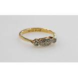 A mid century three stone diamond ring, in a rub over setting, set in yellow and white metal stamped