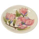 A Moorcroft Magnolia pattern ivory ground plate, stamped in green Moorcroft and signed WM, 26cm diam