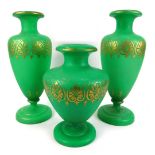 Three Victorian green glass vases, comprising a pair, of green glass blown decoration with gilt acan