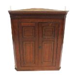 A George III oak hanging corner cupboard, with dentil moulded cornice, and two panelled doors, 103cm