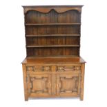 An 18thC oak and elm dresser, with boarded plate rack top, two panelled drawers over two doors, on s