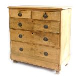 A Victorian stripped pine chest of drawers, the top with a moulded edge above two short and three lo