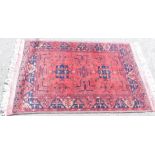 An Afghan Bokhara red ground rug, the central field decorated with two medallions and flowers, withi