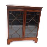 An Edwardian walnut bookcase, with scoop carved frieze, two astragal glazed doors, and bracket feet,