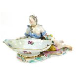 A 19thC Meissen porcelain figural sweetmeat dish, modelled as a partially clad lady holding a large