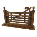 An early 20thC oak pipe stand, formed as a five bar swing gate, with seven slots, 21cm high, 34cm wi