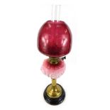 A Victorian cranberry glass oil lamp, with an opaline pink reservoir and cranberry glass shade, on b