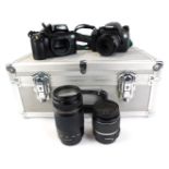An aluminium camera carry case and various cameras, comprising a Canon EOS 550D, with Canon compact