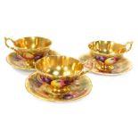 A set of three Aynsley Orchard Gold pattern tea cups and saucers, each painted with fruit by N Brunt