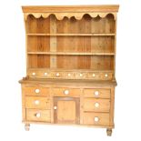 A Victorian stripped pine kitchen dresser, with plate rack top having seven spice drawers with ceram