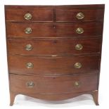 A George III mahogany bow front chest of two short and four graduated drawers, with brass oval back