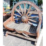 An unusual garden seat, with water wheel back, serpentine seat, and X shaped ends, 120cm wide.