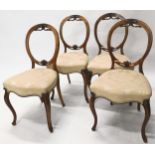A set of four Victorian walnut balloon back dining chairs, each with a cream upholstered padded seat