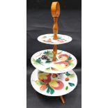 A three tier Italian pottery and wooden cake stand, painted with flowers, on wooden stand, with circ