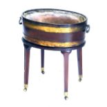 A Regency mahogany wine cooler, with brass banded oval vessel with loop handles and liner, the base