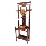 An Edwardian mahogany marquetry hall stand, with a shield shaped mirror and brass pegs, above a draw