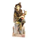 An Art Deco style gilt and copper patinated spelter figure of Pierrot, seated on a marble base, 34cm