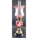 A 20thC oil lamp, with clear glass funnel, amethyst coloured glass ribbed shade, cranberry style res