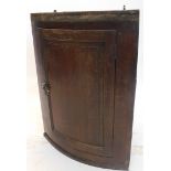 A George II oak bow front hanging corner cupboard, with fielded panel door, moulded cornice, 92cm hi