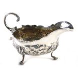 A George III silver sauce boat, by Imperial Mint, with flying scroll handle, repousse decorated flor