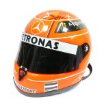 A Shoei motorcycle helmet, in orange, with Bridgestone and Pertronix Mercedes F1 advertising in oran