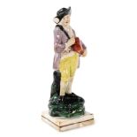 A 19thC Staffordshire pearl glazed figure of a youth with a hurdy gurdy, on a naturalistic base with