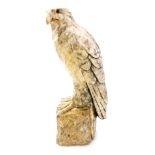 A 19thC Continental carved alabaster figure of an eagle, with glass eyes, perched on a stylised rock