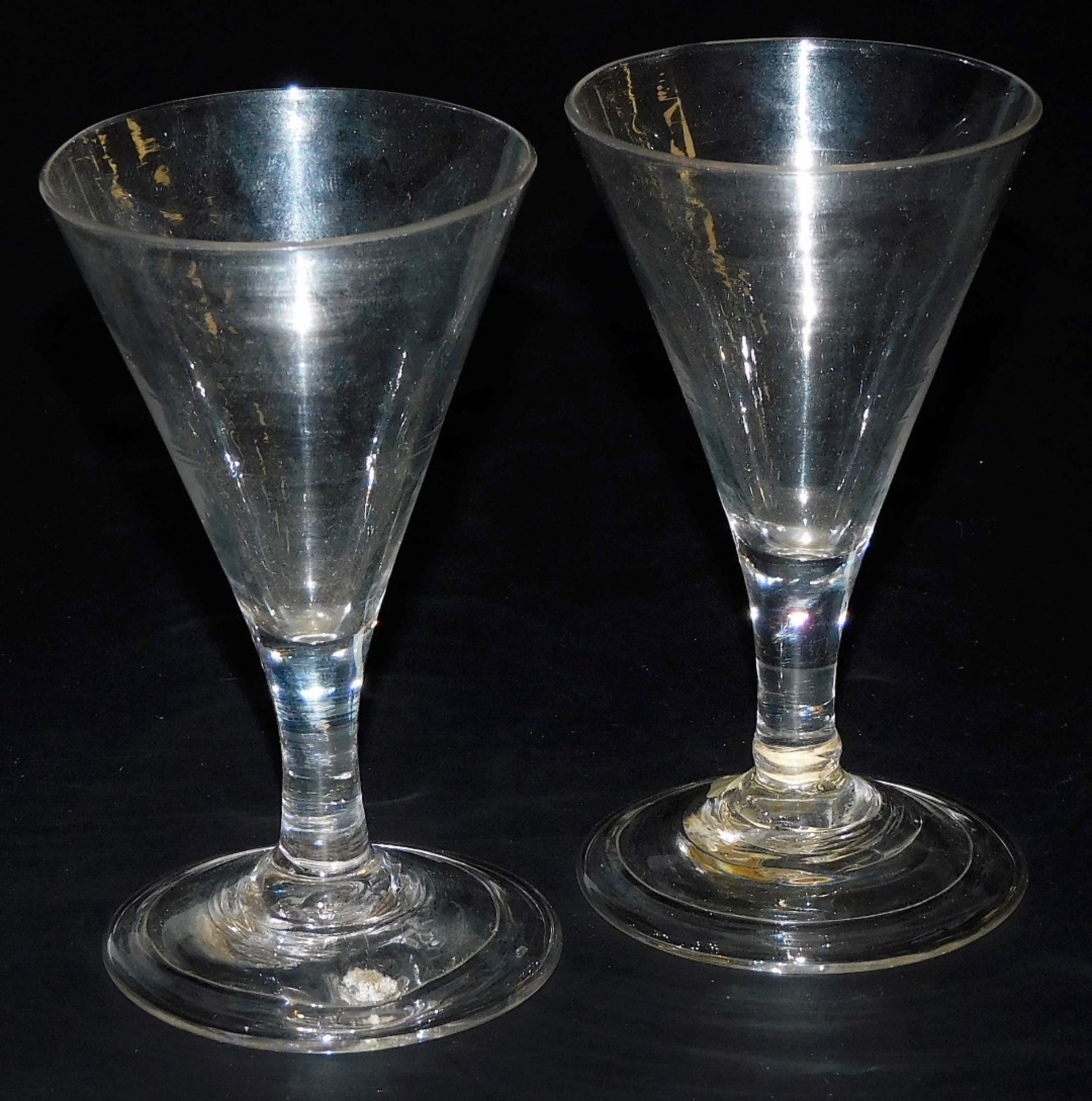 A pair of George III wine glasses, the funnel shaped bowl raised on a straight stem, over a conical