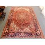 A Persian Heriz type rug, decorated with flowers, leaves, scrolls, in blue, cream, pink, on a red gr