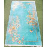 A Chinese wall rug, decorated with flowers, on a jade green ground, possibly 1920s, 118cm x 207cm.