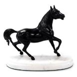 A late Victorian small spelter figure of a horse, in animated pose, raised on a white marble plinth,
